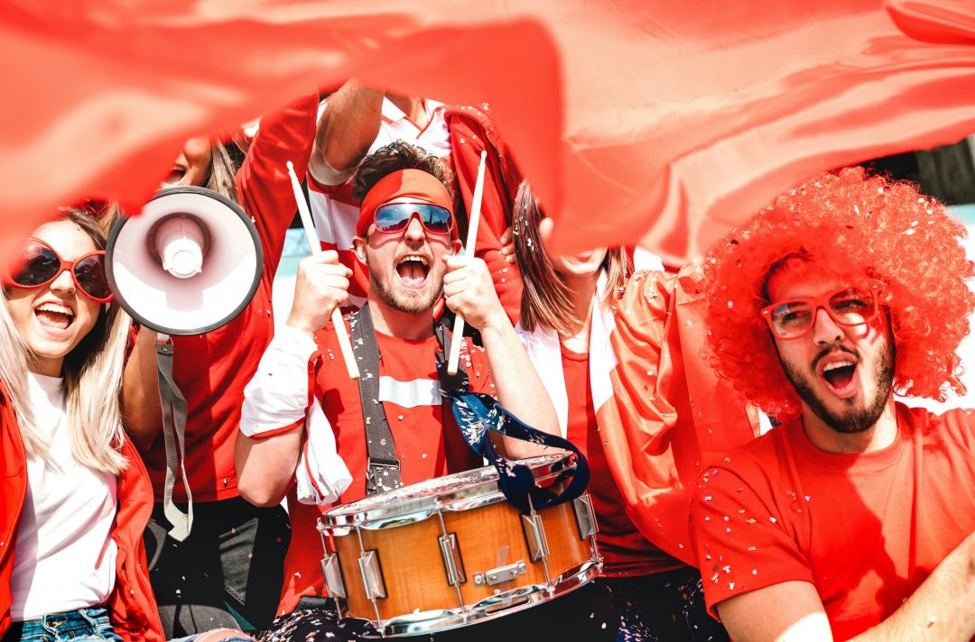 Menschen in Rot und Weiß schwenken Fahnen in einer Versammlung.